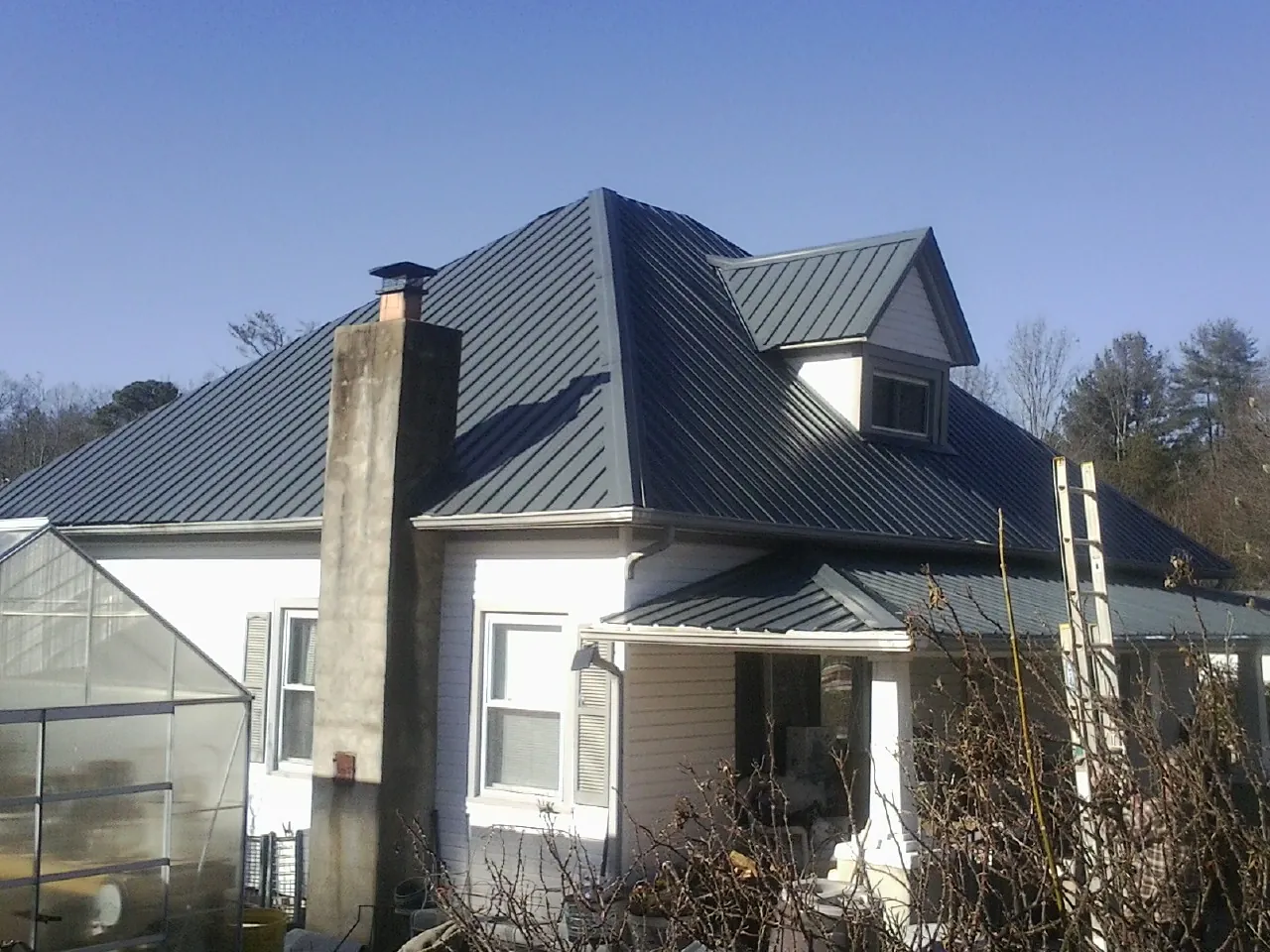 Dark blue standing seam metal roof on a white farmhouse with dormer — Slate & Tile Roof Repair by Roofing Brothers in Cannon Falls