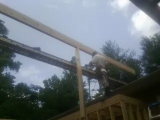 Carpenter setting a ridge beam over a new addition frame — Ice Dam Removal by Roofing Brothers in Cannon Falls