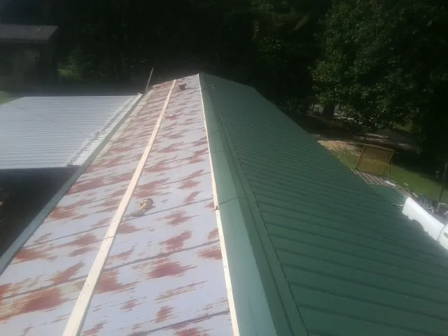 Old rusted panels beside newly installed green metal roofing — Wind Damage Roof Repair by Roofing Brothers in Cannon Falls