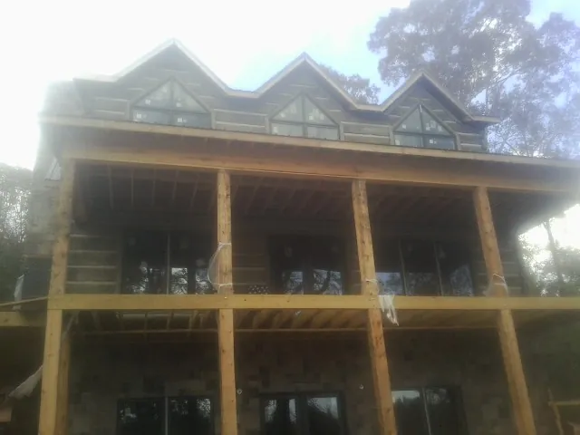 Dormers and porch framing on a large log home under construction — Roof Coating work by our crew in Cannon Falls
