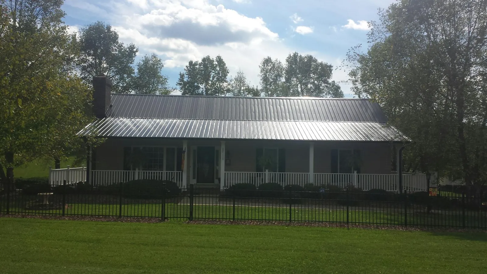 Gray metal roof on a brick ranch with a full width front porch — Gutter Guard Installation work by our crew in Cannon Falls