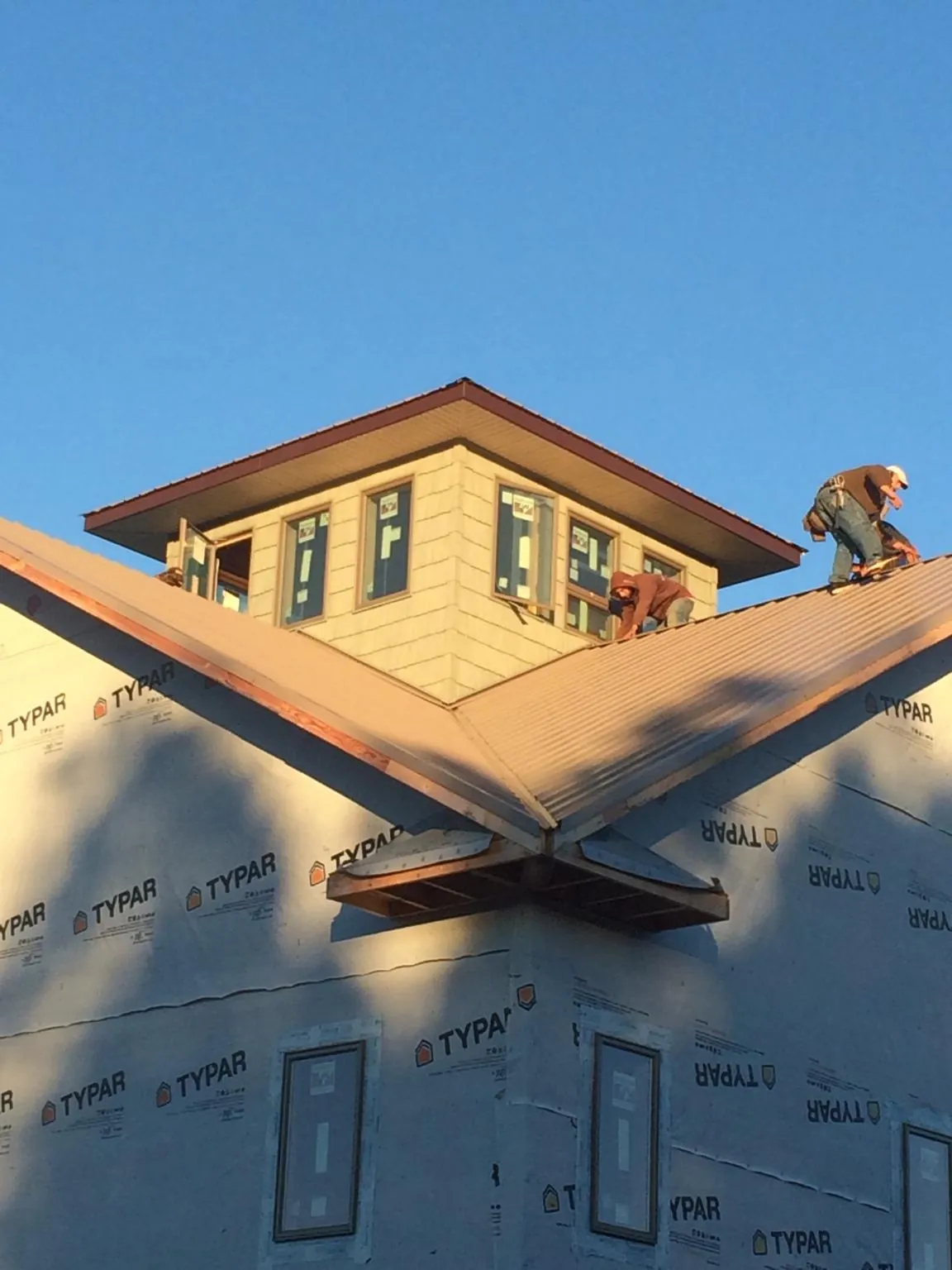 Roofers working around a rooftop cupola on a new metal roof at sunset — Roof Waterproofing in Cannon Falls by Roofing Brothers